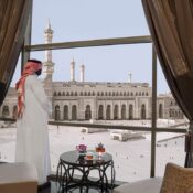 A man standing in hotel room in front of Masjid A-Haram, mecca.