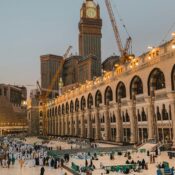 A wide angle of Masjid-Al-Haram with pilgrims while showing clock tower in the background