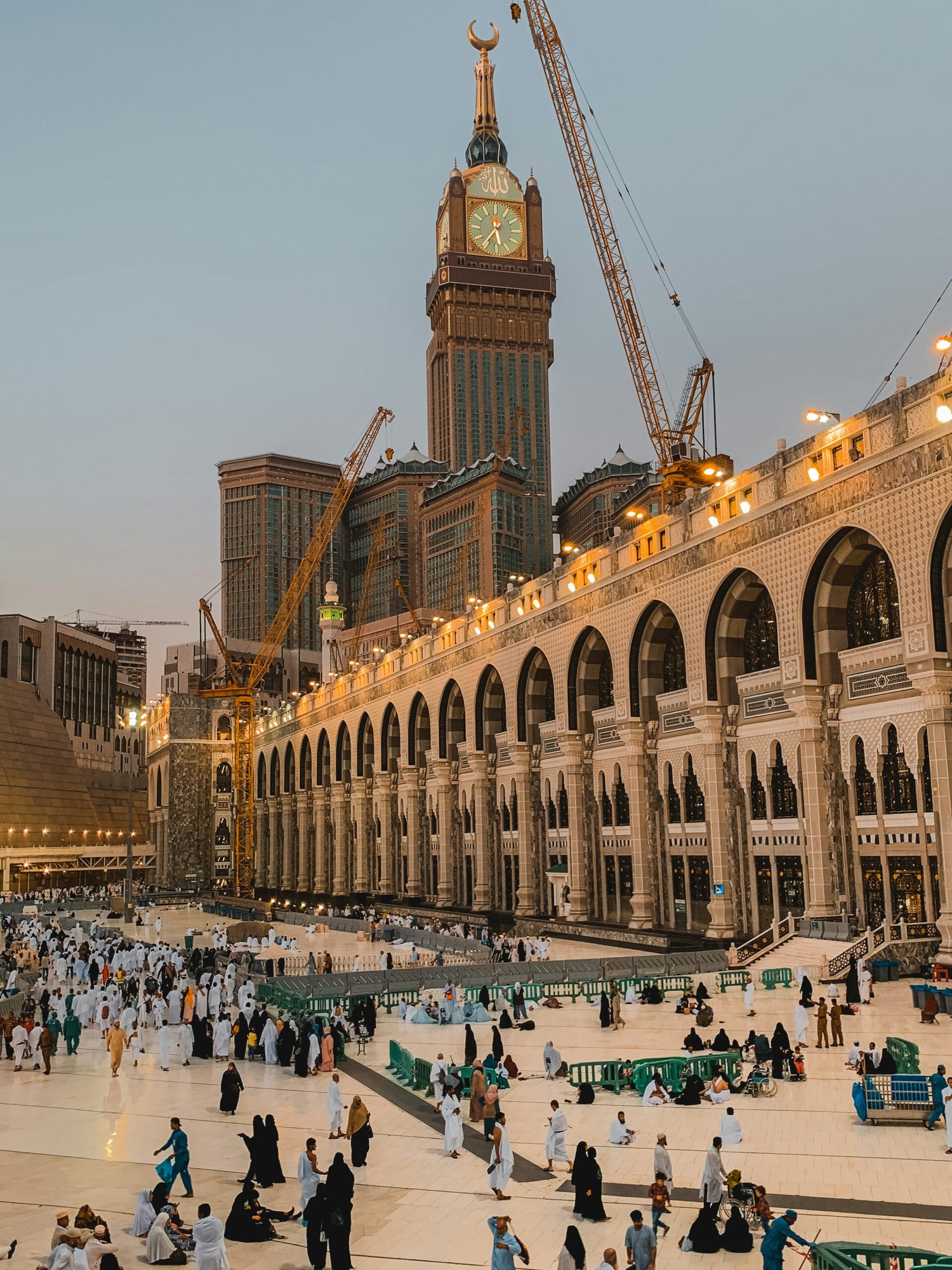 A wide angle of Masjid-Al-Haram with pilgrims while showing clock tower in the background